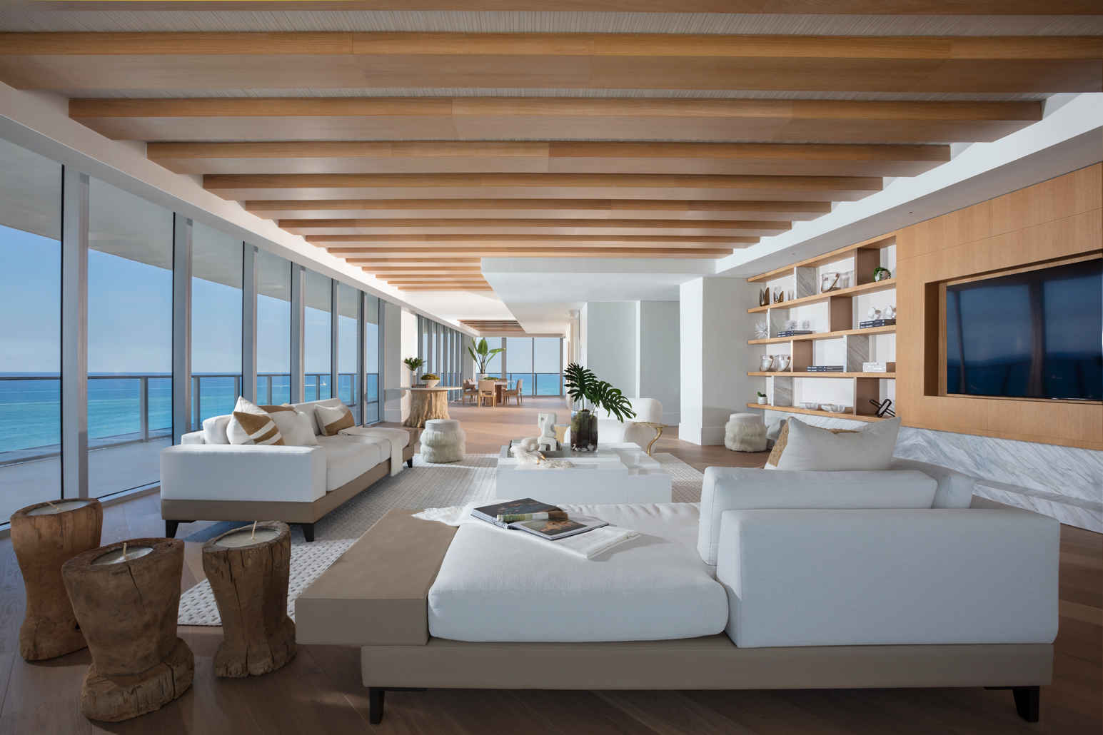 Modern living room with ocean view, wooden ceiling, and white furniture.